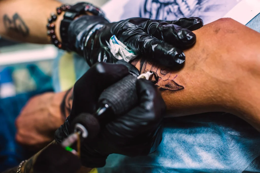 hands-drawing-tattoo-arm-with-needle-machine