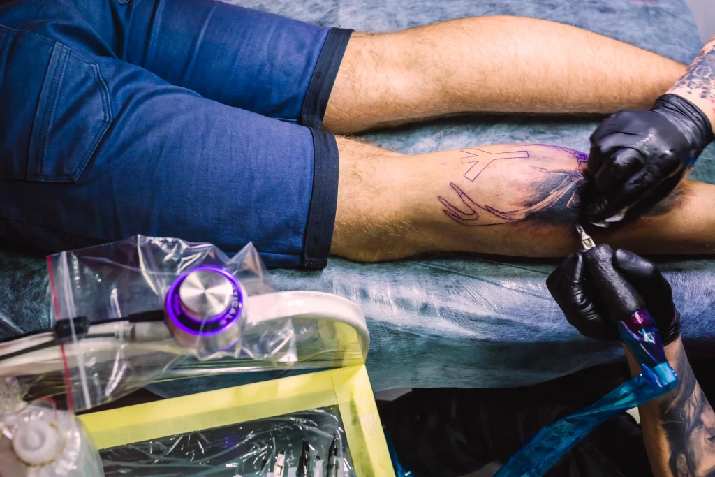 hands-making-tattoo-leg-with-machine