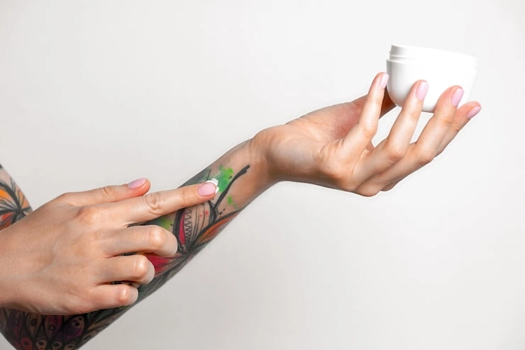Applying cream to a tattooed arm