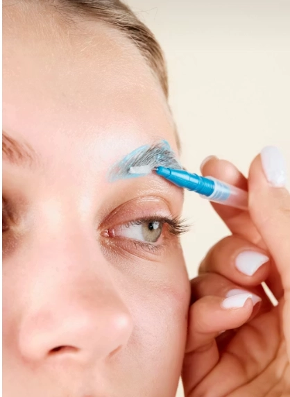 a woman with a blue eyeliner brush on her eye